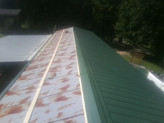 Old rusted panels beside newly installed green metal roofing — Wind Damage Roof Repair by Roofing Brothers in Lake Lure