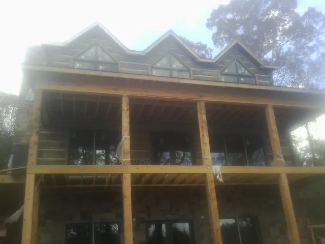 Dormers and porch framing on a large log home under construction — Roof Coating work by our crew in Lake Lure