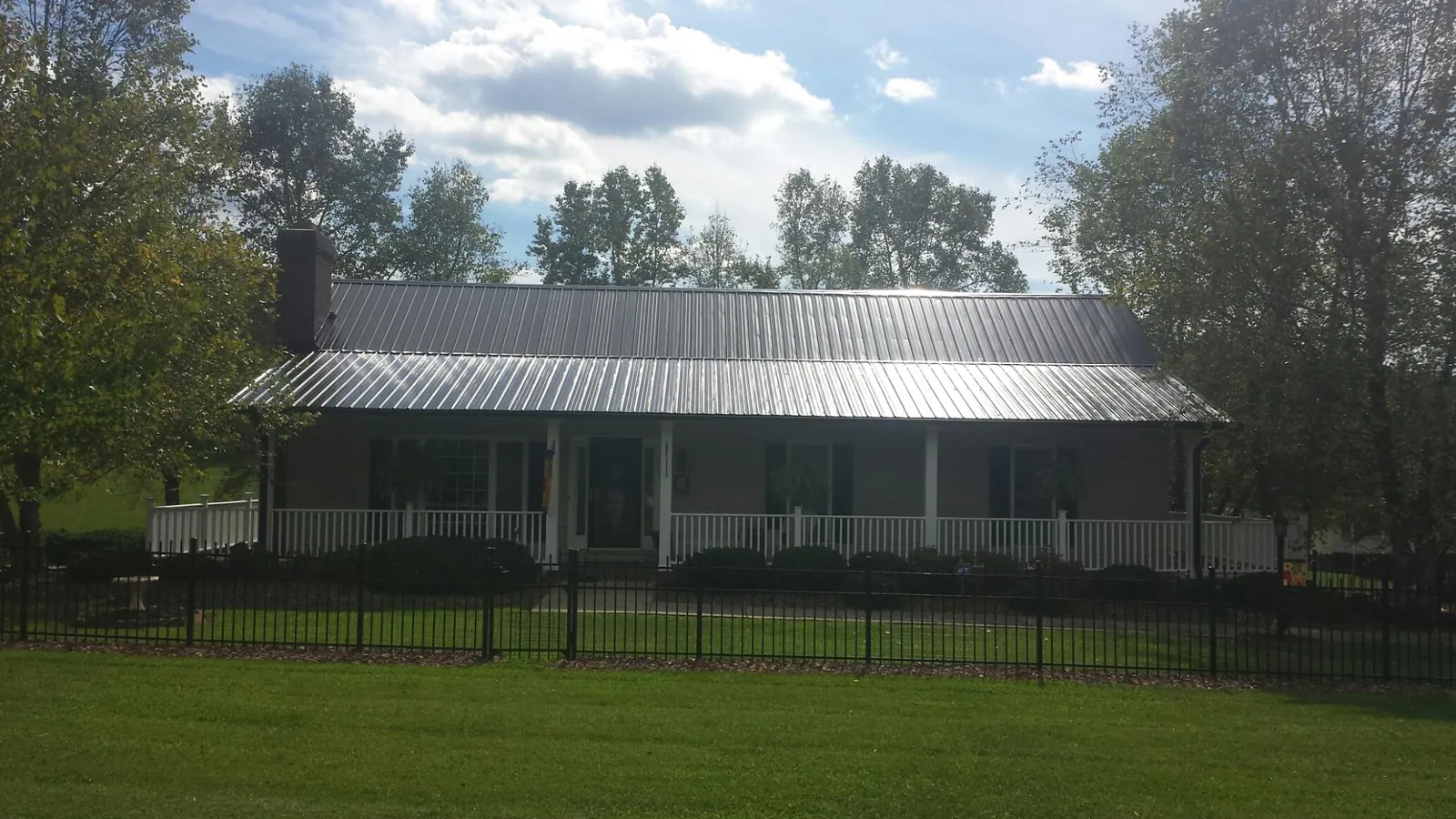 Gray metal roof on a brick ranch with a full width front porch — Gutter Guard Installation work by our crew in Lake Lure