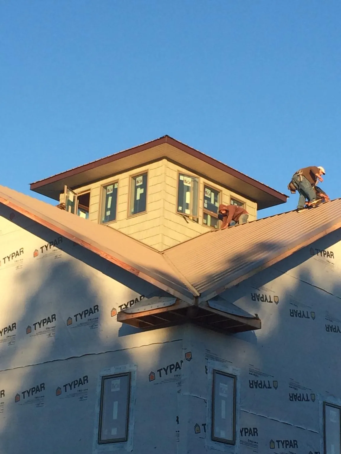 Roofers working around a rooftop cupola on a new metal roof at sunset — Roof Waterproofing in Lake Lure by Roofing Brothers